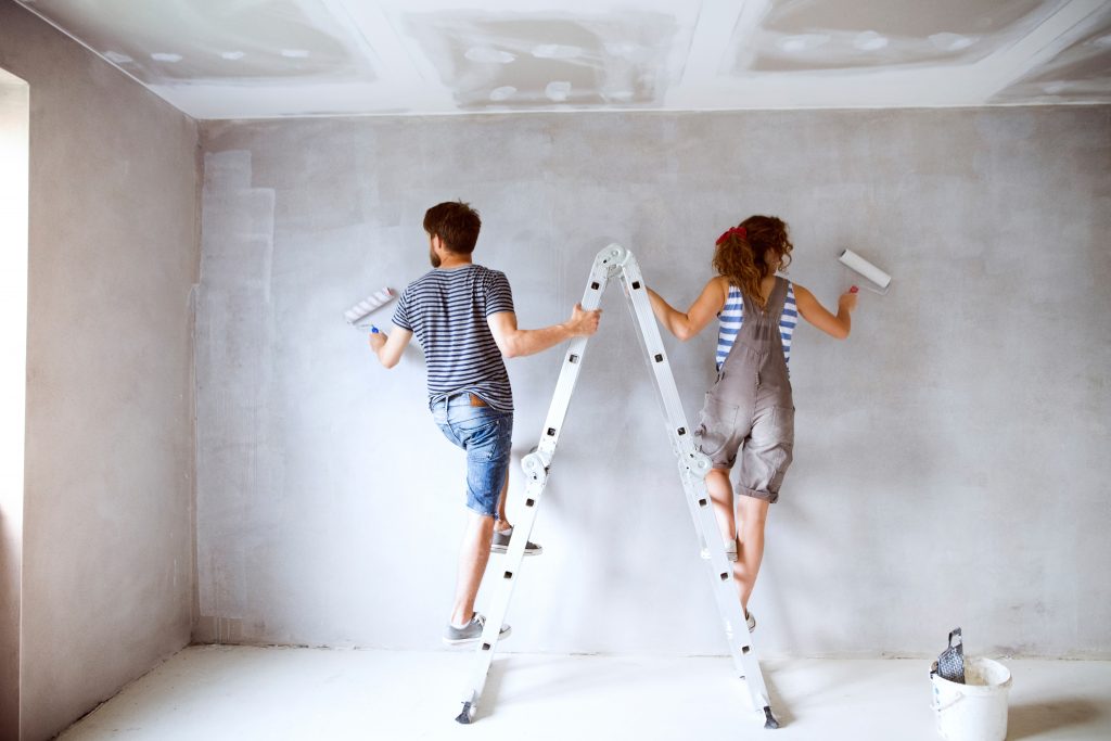 Young couple painting walls in their new house